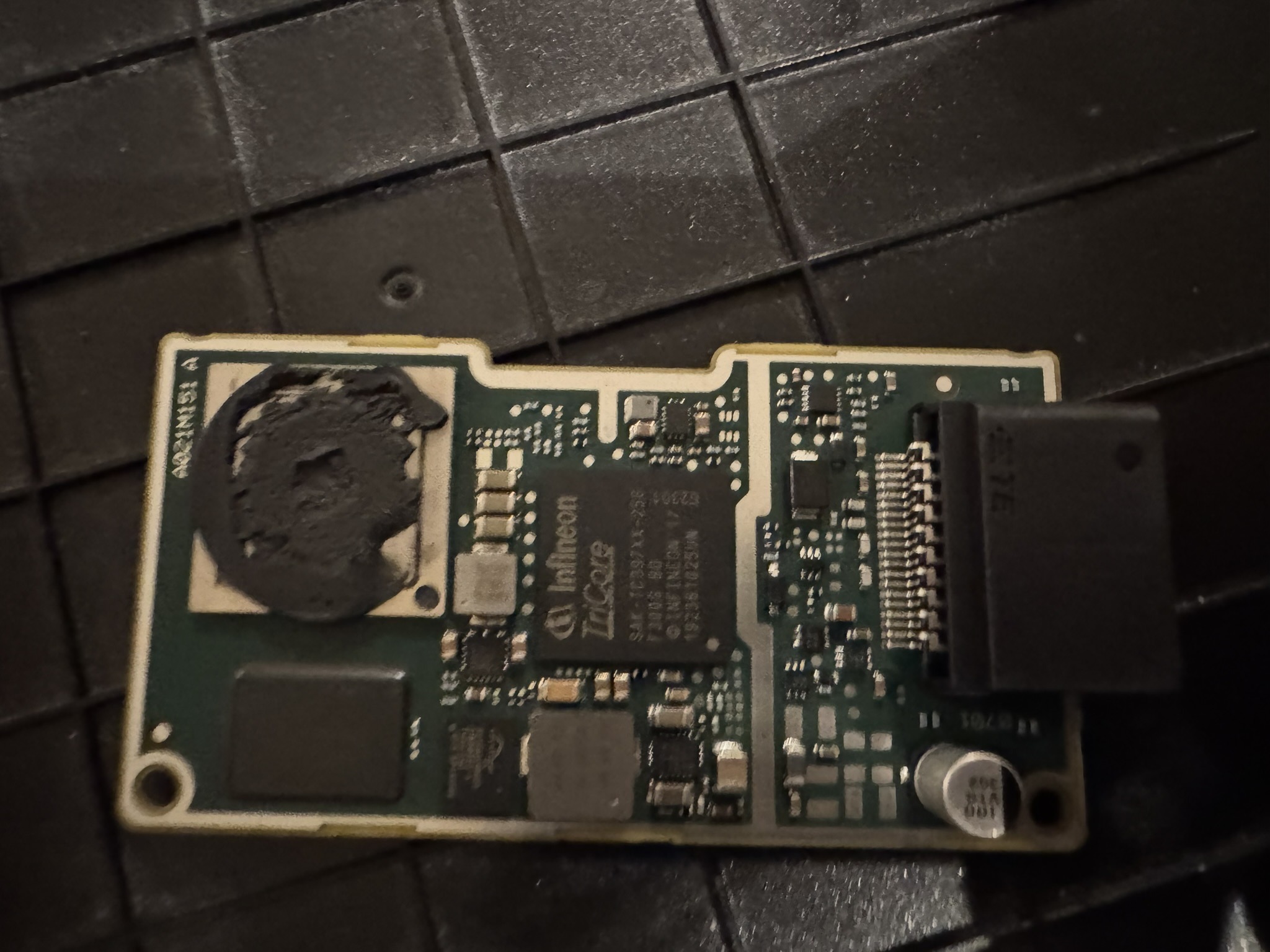Front view camera module board with an Infineon TriCore TC397 in the middle, a lens mount covered in black sealant on the left and a connector on the right